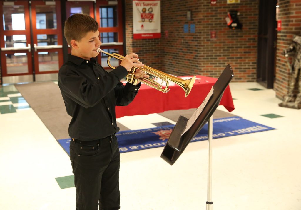 Man playing a saxophone in a school setting.